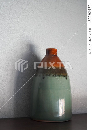 beautiful gradient orange and black and green ceramic vase on brown wooden floor, white wall background, object, decor, fashion, ancient, copy space 123592471