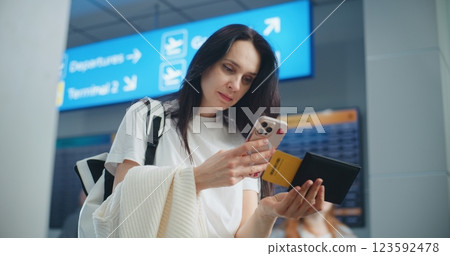 Crowded Airport Terminal: Woman Scanning Plane Ticket Using Phone to Check Flight Information 123592478