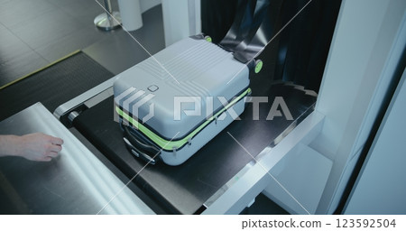 Airport Terminal: Passenger Takes Suitcase from Conveyor Belt with X-ray Scanning Metal Detector Airport Terminal: Passenger Takes Suitcase from Conveyor Belt with X-ray Scanning Metal Detector 123592504