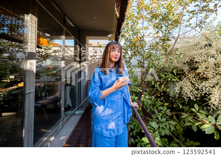 Woman Enjoying Coffee on a Green Balcony Woman Enjoying Coffee on a Green Balcony 123592541