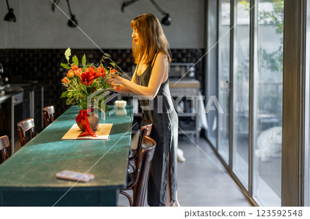 Woman Arranging Flowers in a Modern Kitchen 123592548