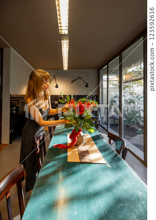 Woman Arranging Flowers in a Cozy Kitchen 123592616