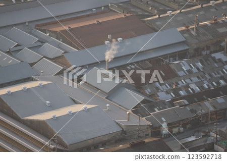 A view of a town with a factory with smoke coming out of its chimneys, seen from a high-rise building 123592718