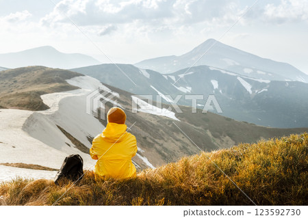 A tourist in yellow jacket sits on the edge of a mountain A tourist in yellow jacket sits on the edge of a mountain 123592730