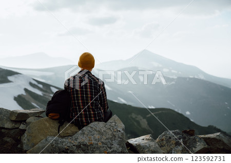 A tourist sits on the stones on the edge of a mountain 123592731