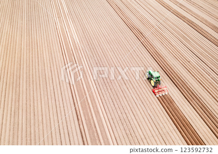 Aerial view of a tractor working on a plowed farmland Aerial view of a tractor working on a plowed farmland 123592732