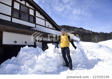 一位老人正在清除屋頂上的積雪 一位老人正在清除屋頂上的積雪 123593199