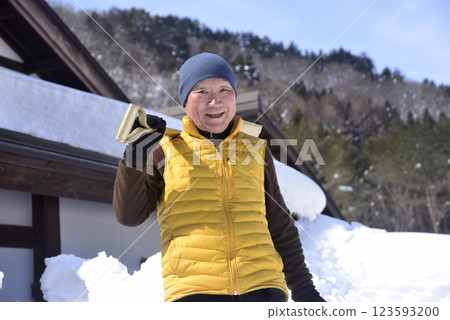 一位老人正在清除屋頂上的積雪 123593200