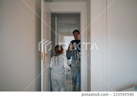 Young caucasian girl and adult caucasian male enjoy festive decorations at home Young caucasian girl and adult caucasian male enjoy festive decorations at home 123593590