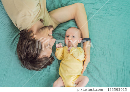 A father and his newborn baby lie on a soft muslin swaddle head to head, sharing a tender moment of closeness and bonding that highlights new beginnings and gentle parenting 123593915