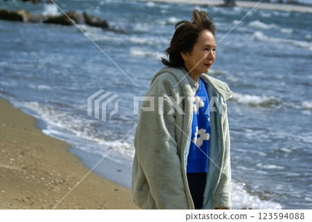 Senior woman walking on the beach in winter, portrait Senior woman walking on the beach in winter, portrait 123594088