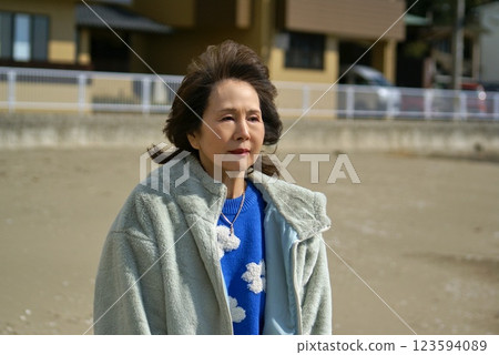 Senior woman walking on the beach in winter, portrait Senior woman walking on the beach in winter, portrait 123594089