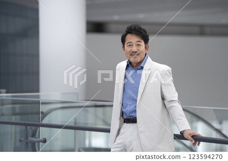 A man in his mid-50s wearing a white jacket smiling and looking at the camera 123594270