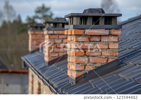 Traditional brick chimneys on slate roof under clear blue sky neural network AI generated 123594882