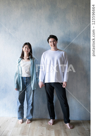 A couple standing close together, gazing at each other with a gentle smile in the light of soft sunlight, full body, looking at the camera, copy space available A couple standing close together, gazing at each other with a gentle smile in the light of soft sunlight, full body, looking at the camera, copy space available 123596664
