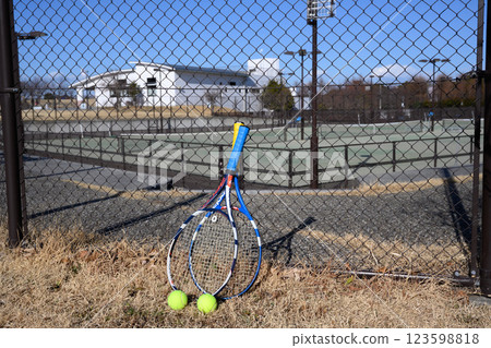 Rackets and balls outside a tennis court 123598818