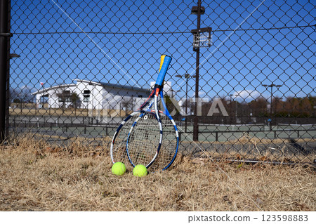 Rackets and balls outside a tennis court 123598883