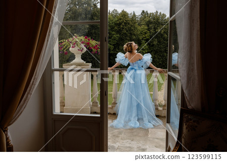 Portrait of an elegant woman in a light blue ball gown in a classic interior by a large window Portrait of an elegant woman in a light blue ball gown in a classic interior by a large window 123599115