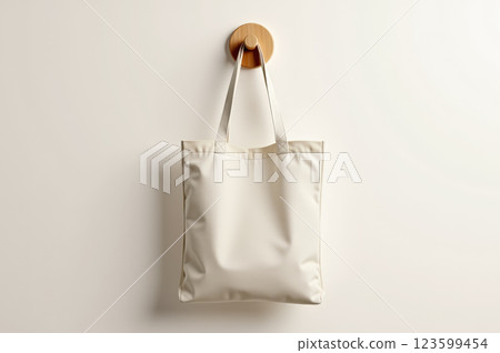 Minimalist white tote bag hanging on wooden hook for modern design mockups. AI generation 123599454