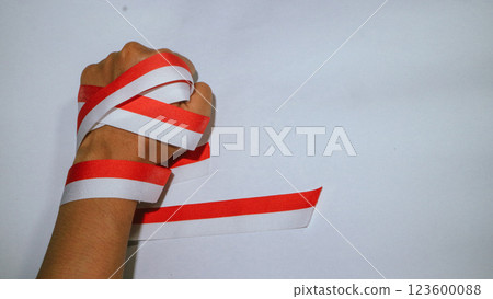 Hand holding red white flag ribbon, celebrate Indonesia independent day on 17 August with isolated background  123600088