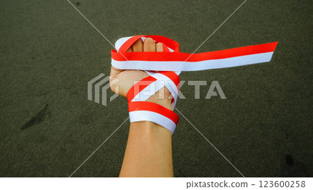 Asian hand holding Ribbon In colors of Indonesia flag red and white, celebrate Indonesia independent day on 17 August with Sandy texture  Asian hand holding Ribbon In colors of Indonesia flag red and white, celebrate Indonesia independent day on 17 August with Sandy texture  123600258