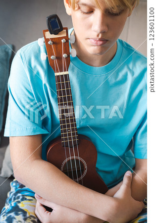 Thoughtful Teen Boy Embracing Guitar. 123601100
