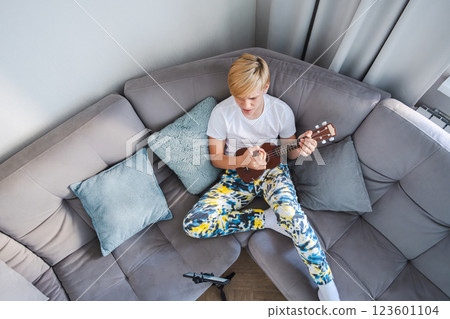 Teen Boy Learning Playing Ukulele from Phone at home. Teen Boy Learning Playing Ukulele from Phone at home. 123601104