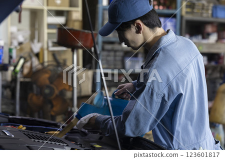 A man maintaining a car A man maintaining a car 123601817