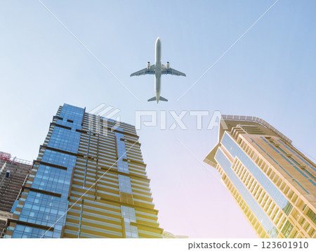 Skyscraper facades on a bright sunny day with sunbeams in the blue sky and passenger aircraft flying over it 123601910