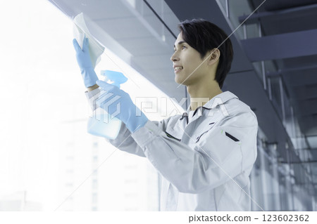 一名年輕的男清潔工正在清潔窗戶。 一名年輕的男清潔工正在清潔窗戶。 123602362