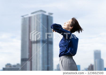 A woman stretching with a cityscape in the background A woman stretching with a cityscape in the background 123602500