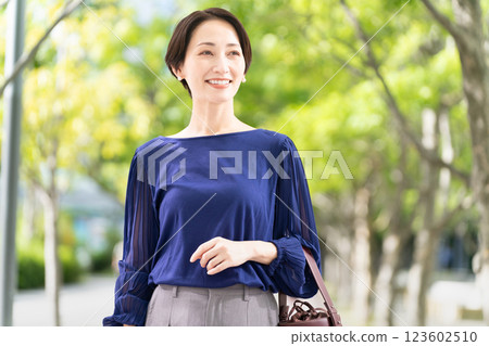 Woman walking along a tree-lined street Woman walking along a tree-lined street 123602510