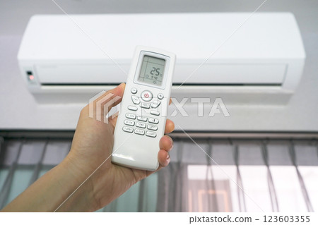 Man's hand using remote control open The air conditioner is cooled to 25 degrees Celsius in his bedroom. Health concepts and energy savings 123603355
