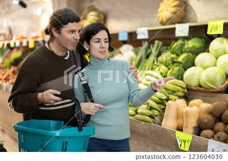 couple stands in a supermarket near a stall and looks at vegetables and fruits couple stands in a supermarket near a stall and looks at vegetables and fruits 123604030