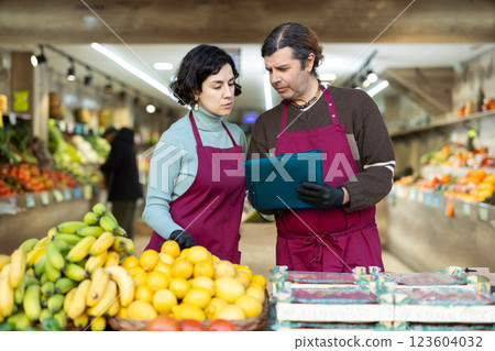 Man and woman store employee with folder of documents takes inventory in vegetable store Man and woman store employee with folder of documents takes inventory in vegetable store 123604032