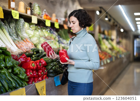 Woman carefully selects red bell peppers in grocery supermarket 123604051