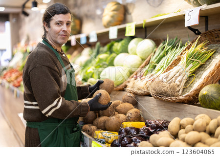 Man shop seller puts cocoanut goods on display case 123604065