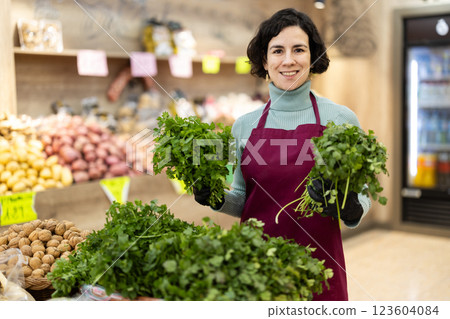 Adult woman seller puts bunches of parsley on display 123604084