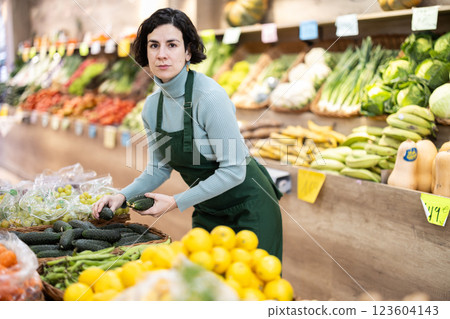 Adult woman seller puts cucumbers on display 123604143