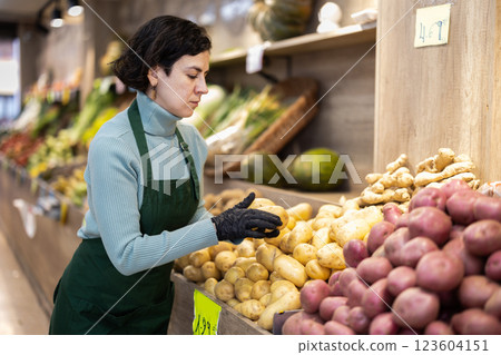 Adult woman seller puts potatoes on display Adult woman seller puts potatoes on display 123604151