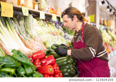 Adult man seller puts zucchini on display 123604169