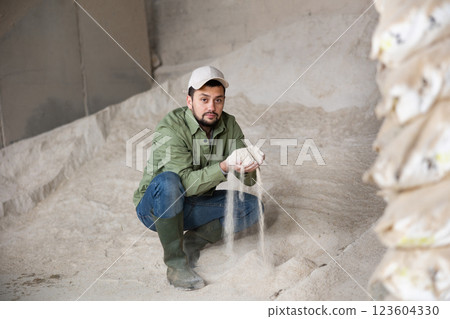 Livestock breeder checking quality of maize meal in farm storage 123604330