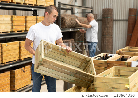 Man florist looking for functional wooden box for growing flowers Man florist looking for functional wooden box for growing flowers 123604336
