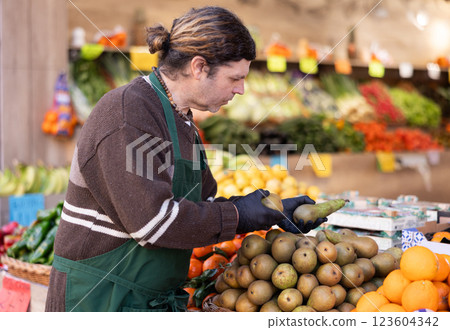Man shop seller puts pear goods on display case 123604342