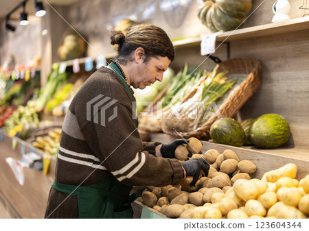 Man shop seller puts potato goods on display case 123604344