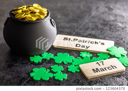 St. Patrick's Day. Green clover leaves decoration and cauldron with golden coins on black table. 123604378