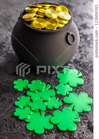 St. Patrick's Day. Green clover leaves decoration and cauldron with golden coins on black table. 123604381