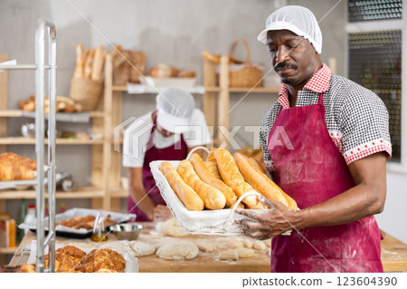 Adult man baker with basket of baguettes Adult man baker with basket of baguettes 123604390