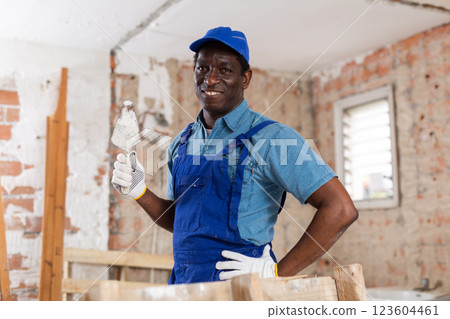 Cheerful plasterer standing with trowel in room under renovation 123604461