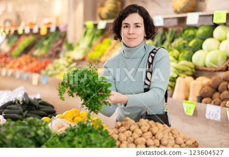 Adult woman chooses parsley in vegetable shop Adult woman chooses parsley in vegetable shop 123604527